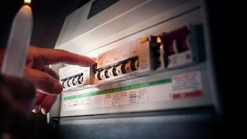 Electricity power outage or blackout emergency turning on or off circuit breaker on electrical fuse board with candle